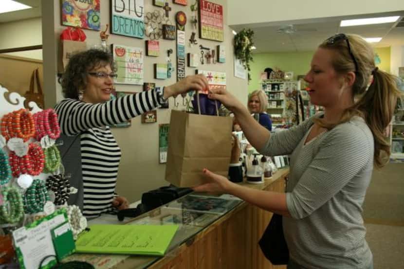 
Cheryl Calvin, owner of The Store in Lake Highlands, hands over gift-wrapped merchandise to...