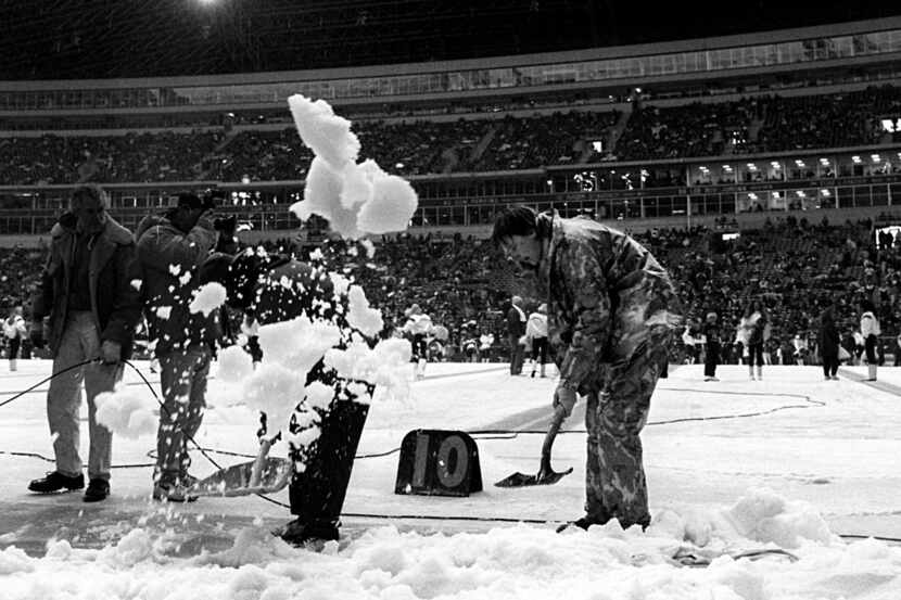 Workers at Texas Stadium work to remove snow from the field prior to the start of the Dallas...