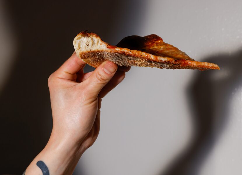 Peter Cho holds up a slice of a cheese pizza to see how much the crust rose while it baked...