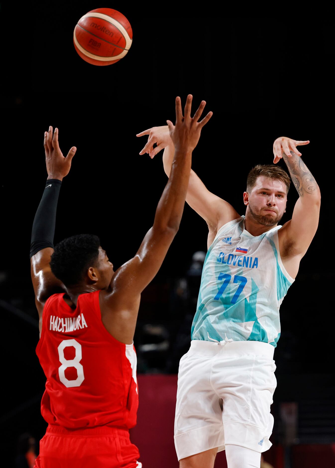Slovenia’s Luka Doncic (77) passes as Japan’s Rui Hachimura (8) defends in a basketball game...