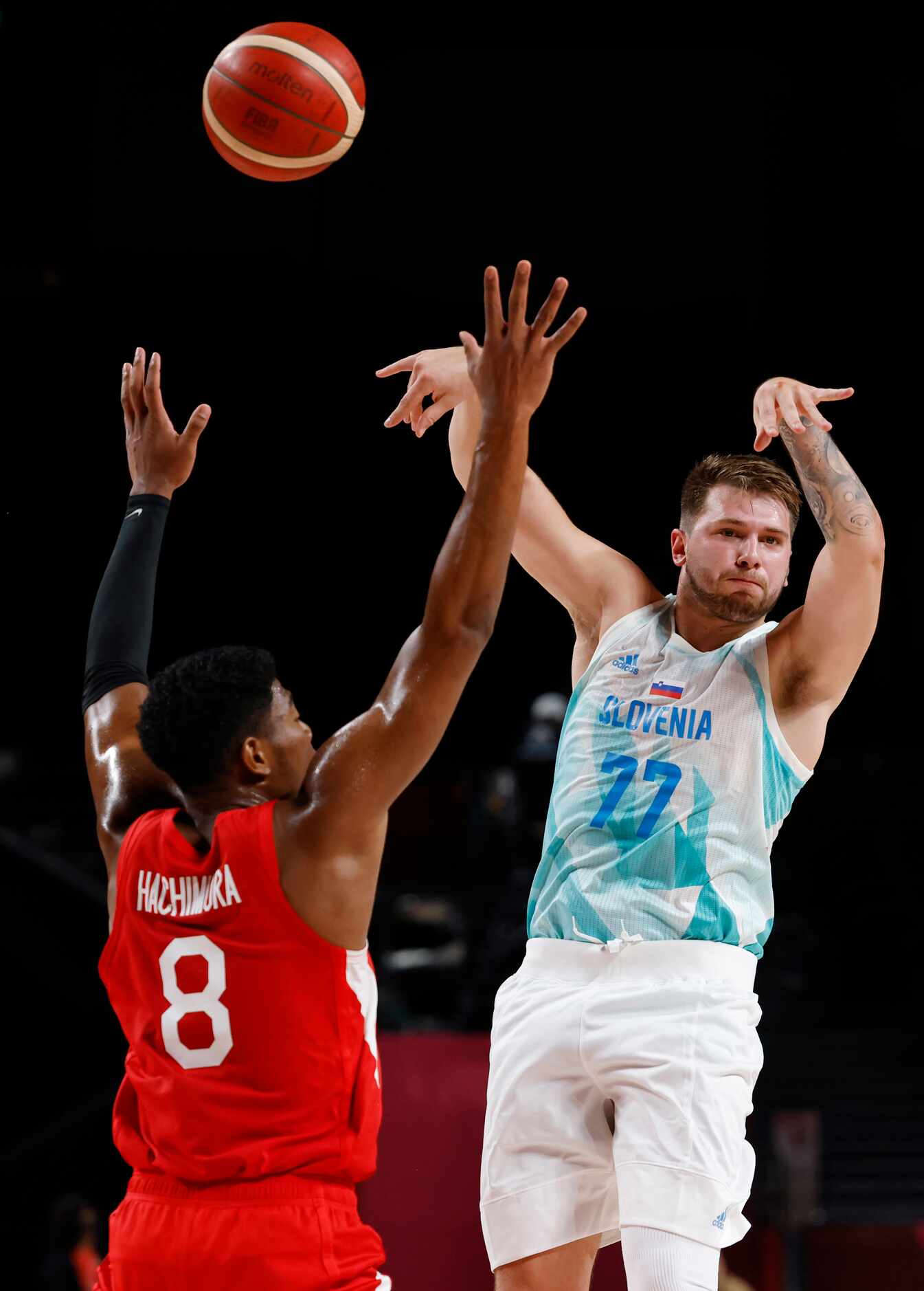 Slovenia’s Luka Doncic (77) passes as Japan’s Rui Hachimura (8) defends in a basketball game...