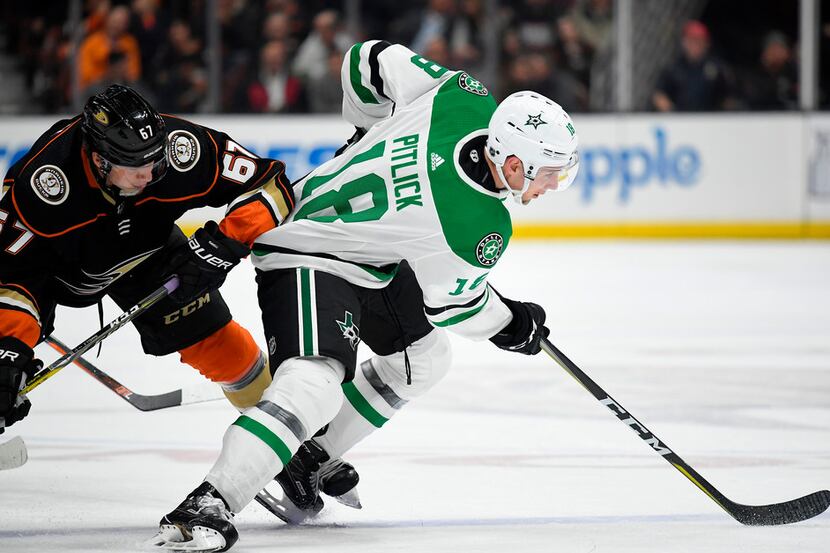 Dallas Stars center Tyler Pitlick, right, passes the puck while under pressure from Anaheim...