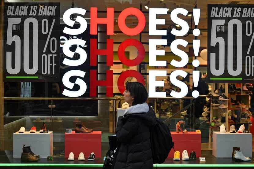 Shoppers pass a promotional sign for 'Black Friday' sales discounts in London, on November...