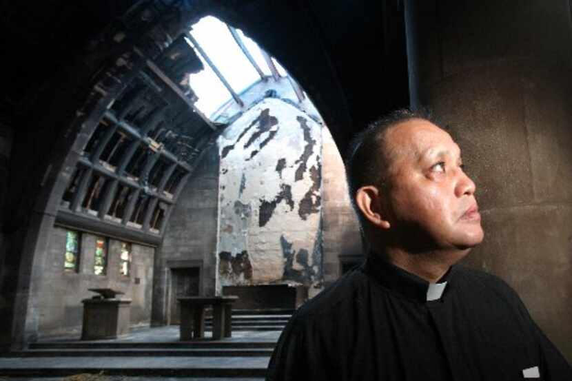 Edmundo Paredes stands in the charred remain of the sanctuary at St. Cecilia Catholic Church...