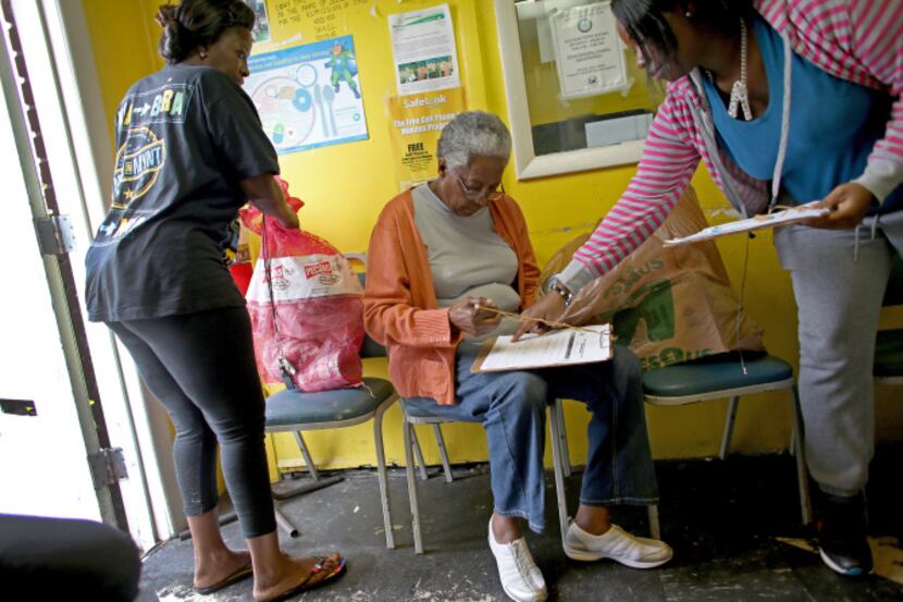 Jeraldine Walker got help filling out a form for a bag of groceries from volunteer Laquanda...
