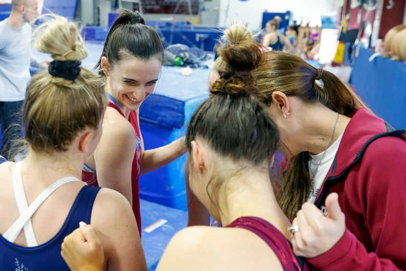 Gymnast Alix Pierce smiles with her teammates as they break from a huddle during practice at...