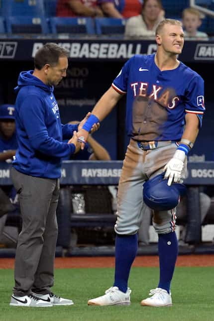 A Texas Rangers trainer (left) looked over Josh Jung after he was hit by a foul ball against...