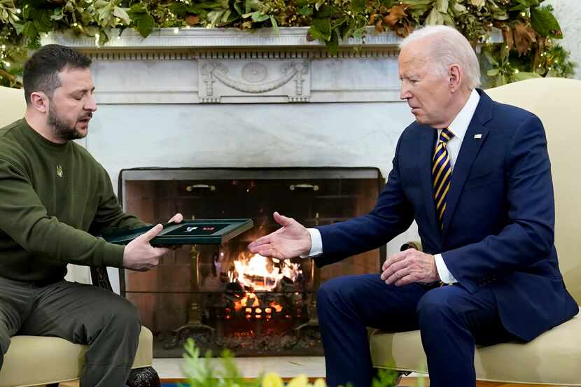 Ukrainian President Volodymyr Zelenskyy speaks as he gives President Joe Biden a gift as...