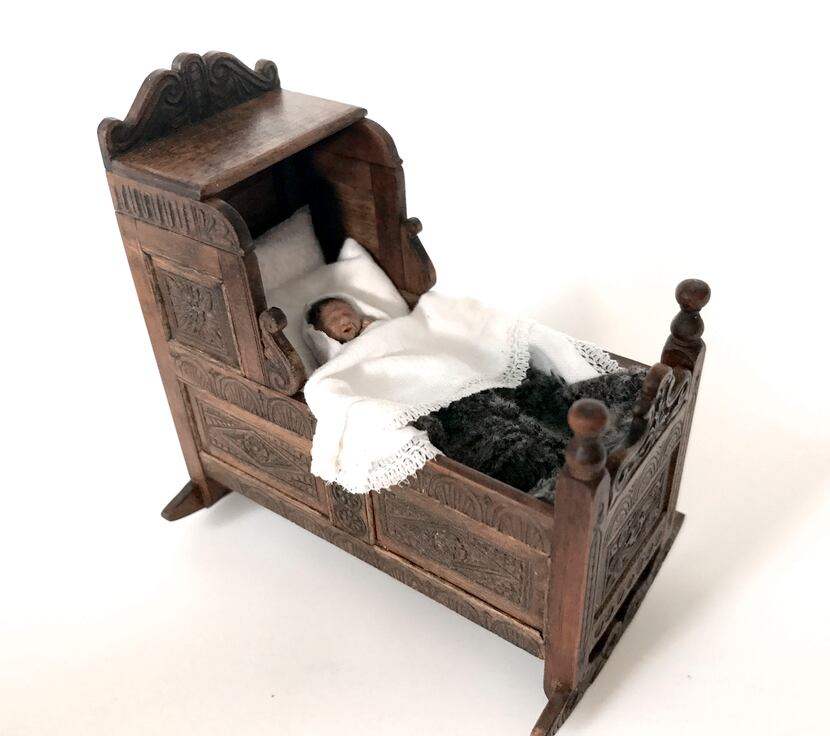 A cradle made by Ann High, with linens and baby made by Kevin Mulvany and Susie Rogers, who...