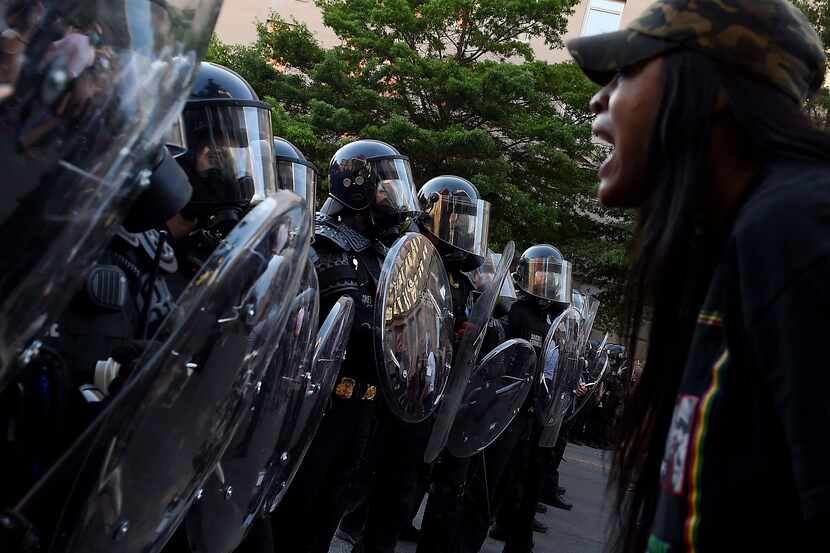 A protester screams in front of a row of police officers during a demonstration against the...