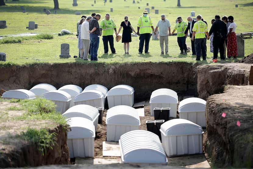 FILE - In this July 30, 2021 photo, a group prays during a small ceremony as remains from a...