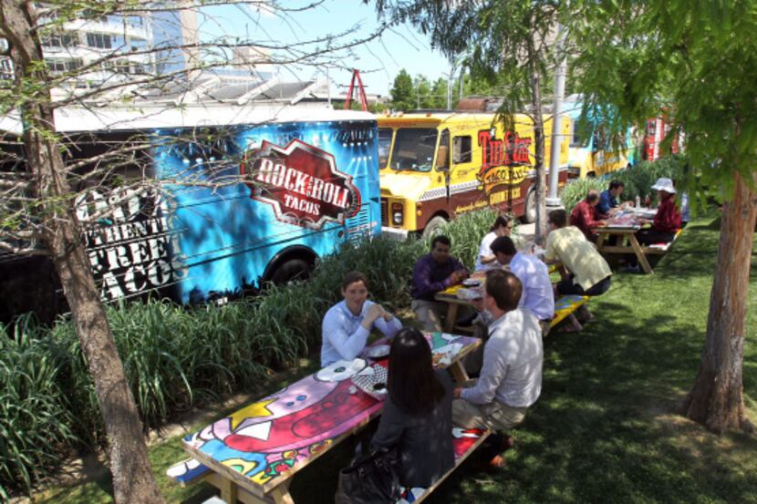 Downtown workers eat lunch at picnic tables near food trucks parked off of Flora Street in...