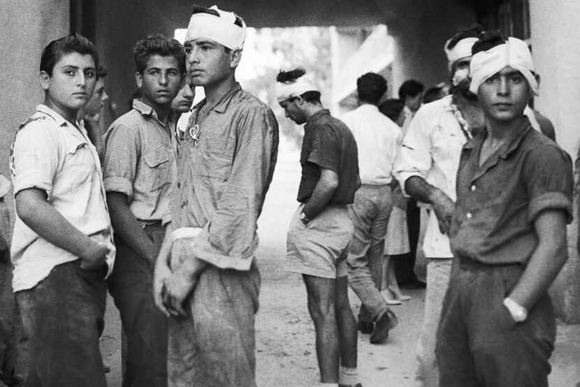 Greek Cypriot youths, some with bandaged heads, stand outside a hospital in Famagusta,...