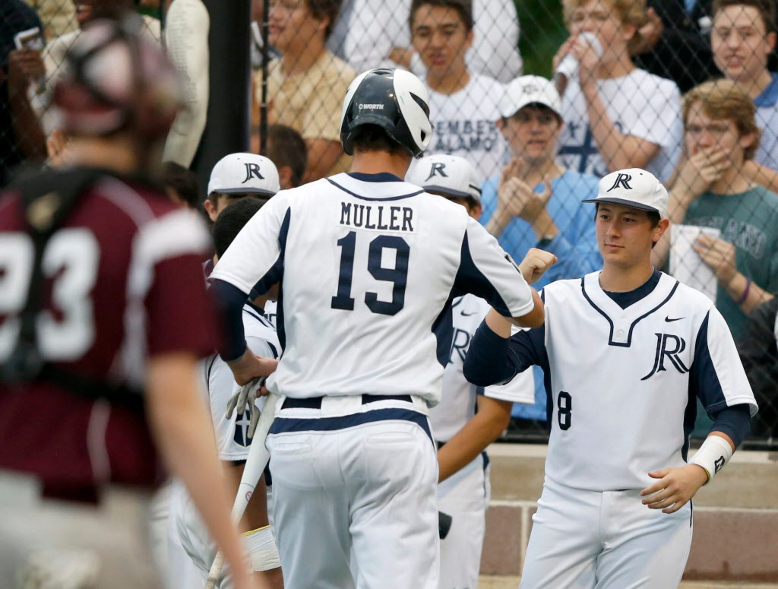 Jesuit's Kyle Muller (19) is congratulated by teammate Cole House (8) after scoring a run in...