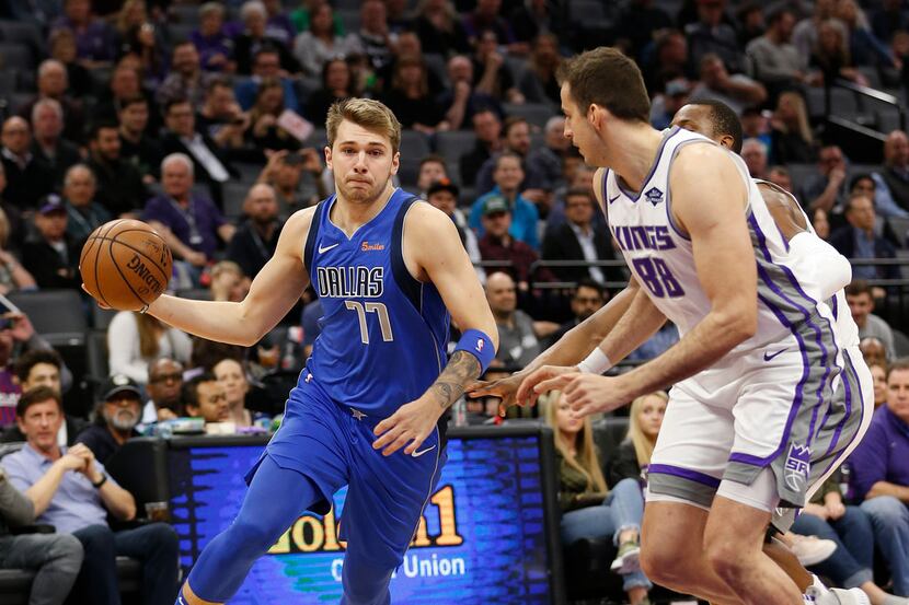 Dallas Mavericks forward Luka Doncic, left, drives to the basket against Sacramento Kings...