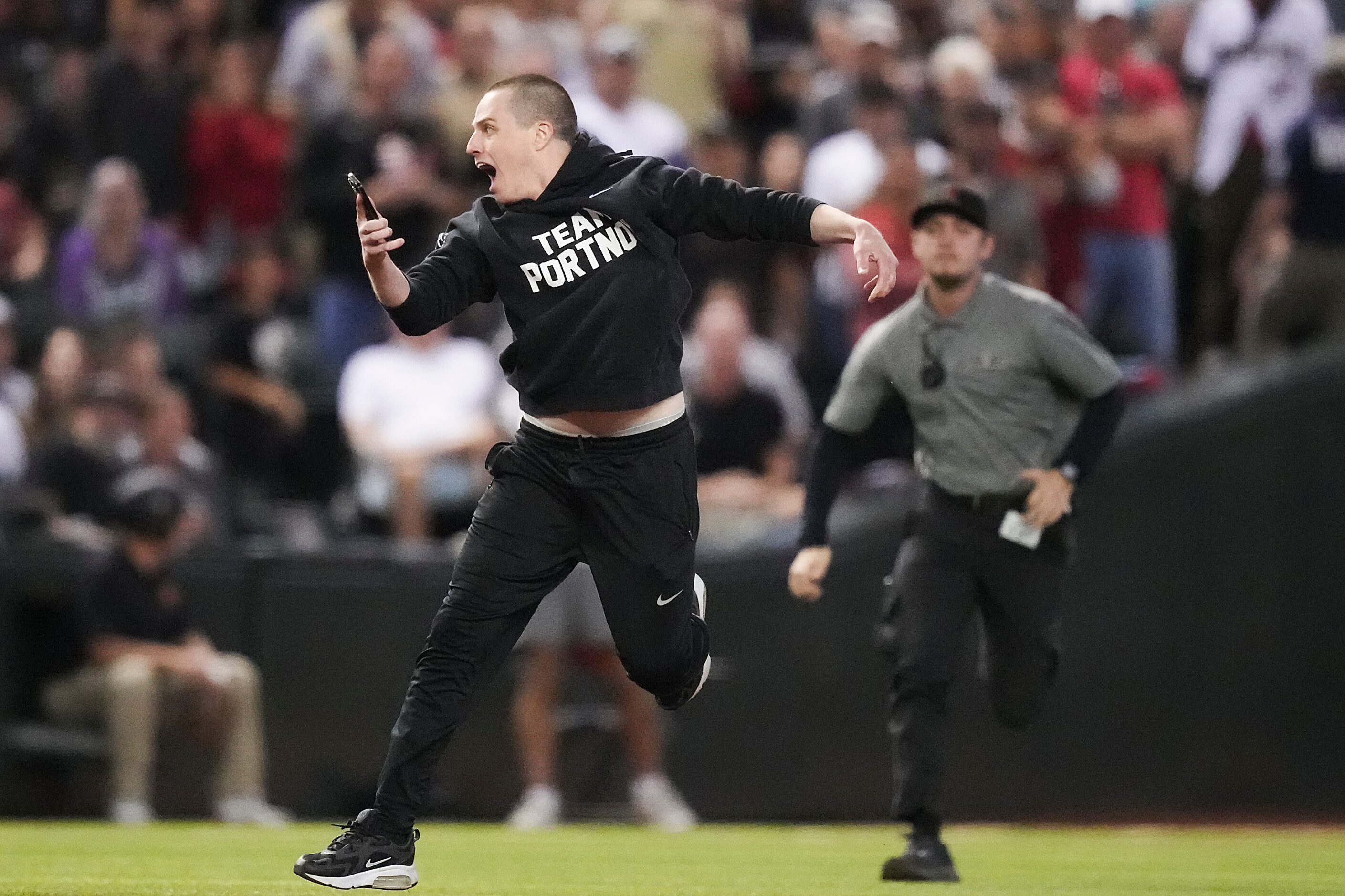 Security chases after a fan who ran onto the field during Game 4 of the World Series between...