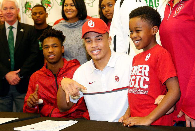 Southlake Carroll defensive back Robert Barnes (center) throws down the Hook'em Horns sign...