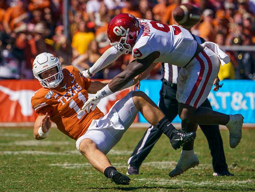 Texas quarterback Sam Ehlinger (11) is hit by Oklahoma linebacker Kenneth Murray (9) at the...