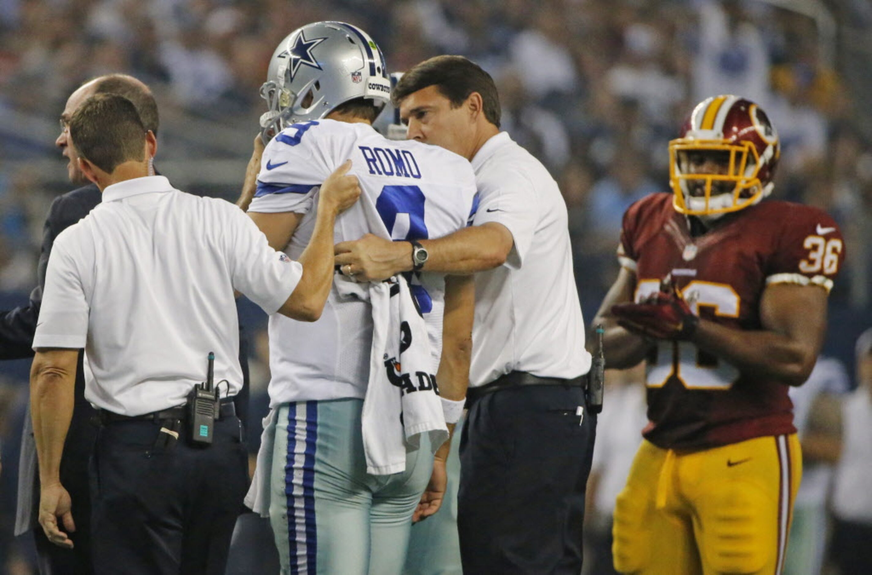 Dallas Cowboys quarterback Tony Romo (9) is helped off the field by trainers after being...