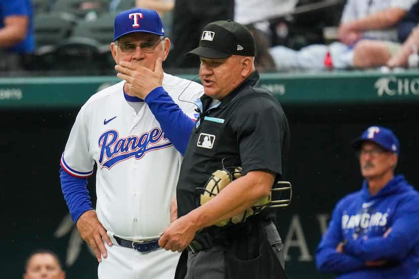 Texas Rangers manager Bruce Bochy confers with umpire Jeff Nelson during the third inning of...