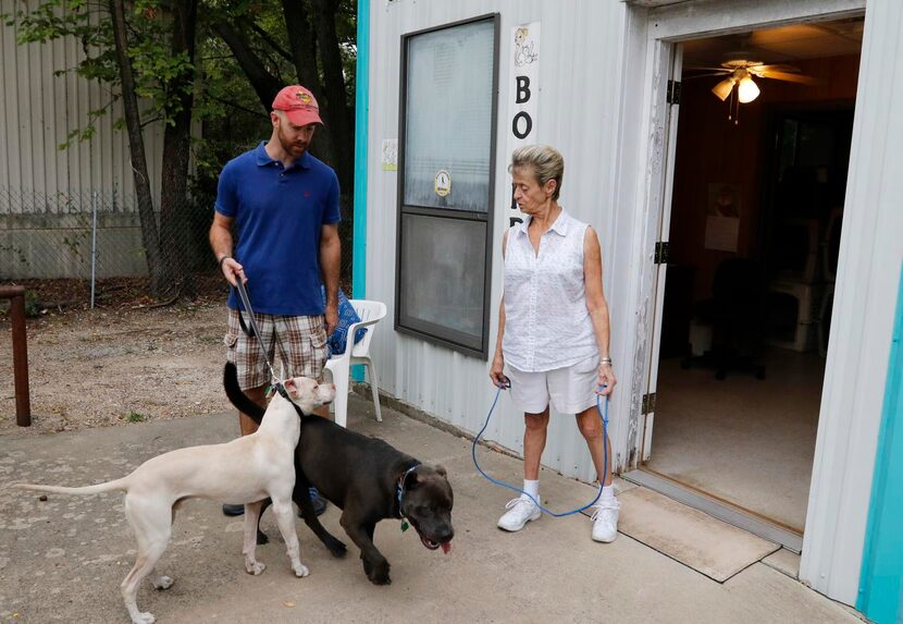 
Carol Merritt (right) talks to Jon Tomell, one of her clients, as he picks up his two dogs...