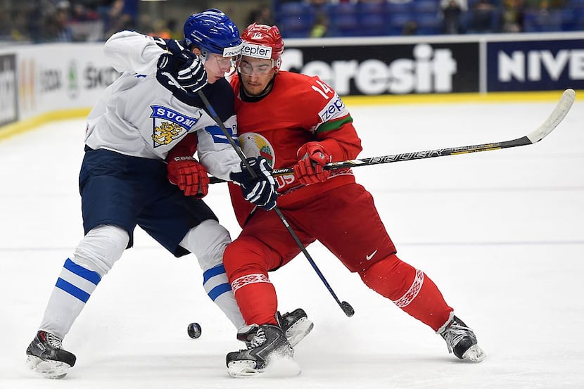 Finland's Esa Lindell (L) and Yevgeni Lisovets of Belarus fight for a puck during the group...