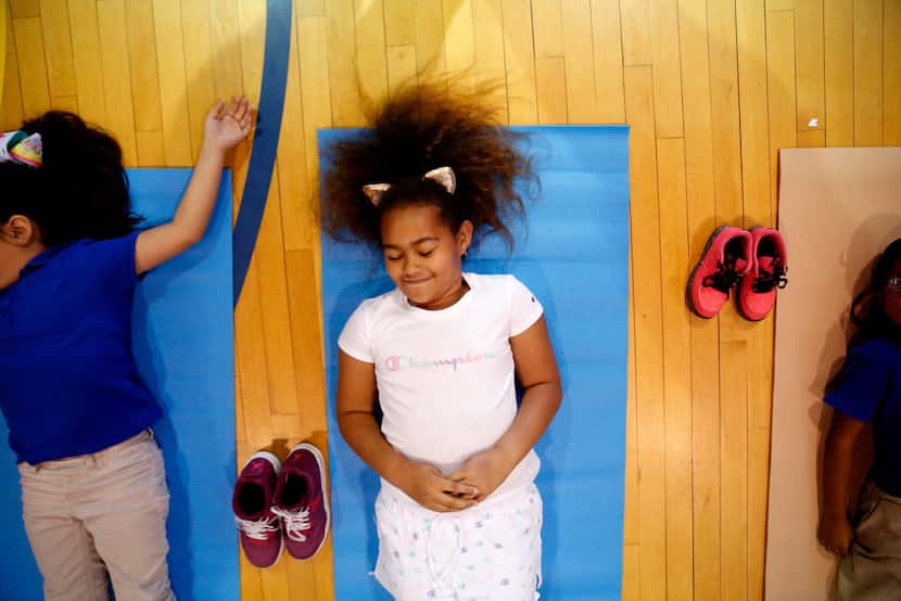 Aiysia Knox, a second-grader in DISD's after-school program, does yoga led by Ebony Smith,...