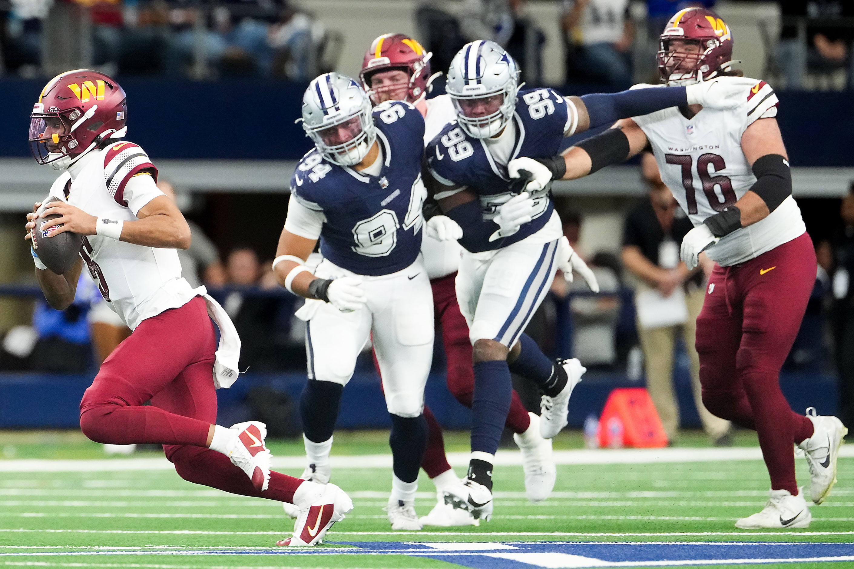 Washington Commanders quarterback Jayden Daniels (5) gets past Dallas Cowboys defensive end...