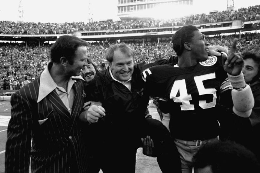 Pittsburgh Steelers coach Chuck Noll leaves the field with Jim Allen (45) who holds up his...