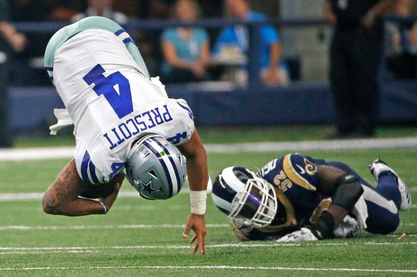 Dallas Cowboys quarterback Dak Prescott (4) is tripped up by Los Angeles Rams inside...