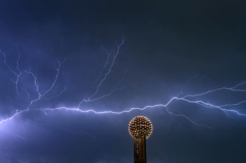 Lightning streaks across the sky behind the Reunion Tower Ball in downtown Dallas Thursday...