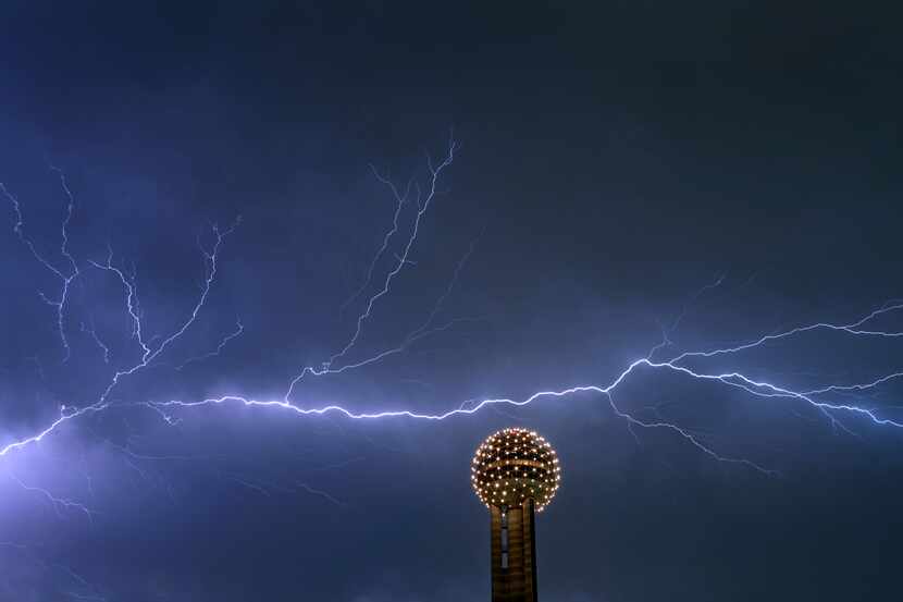 Lightning streaks across the sky behind the Reunion Tower Ball in downtown Dallas Thursday...