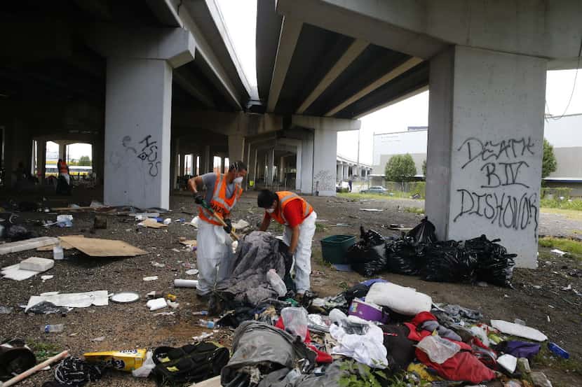 Hazardous material workers throw away tents and property after the city closed a large...