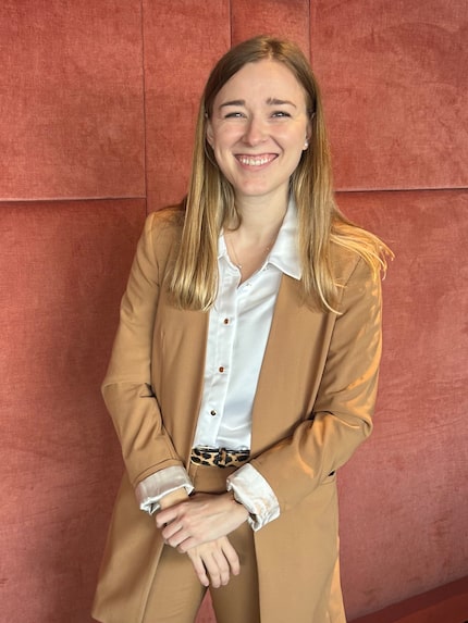 Realtor in tan suit against a red wall