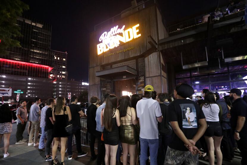Guests wait in line outside of Bottled Blonde in Dallas on Sept. 11, 2020. The bar got...