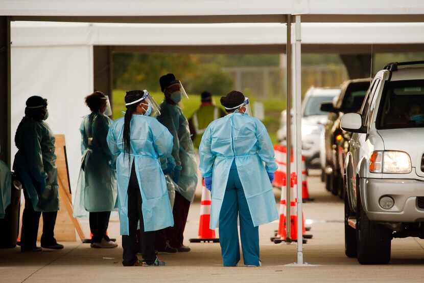 Medical personnel prep and conduct nasal swab tests at a drive-thru COVID-19 testing site at...