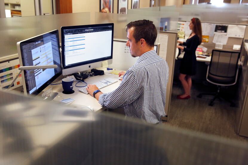 Graphic designers Dylan Rueff (left) and Anne Fox worked at their standing desks at Lockton...