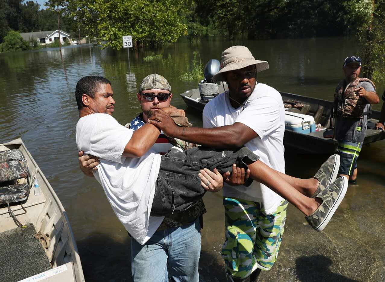 Quintin Sanders is carried to dry land by volunteer rescuers after his neighborhood was...