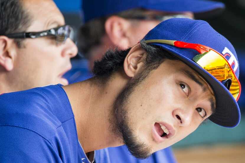 Texas Rangers starting pitcher Yu Darvish watches from the dugout during the third inning...