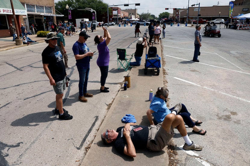 David Skelton (center) lays down to view a partial solar eclipse next to his wife Roberta...