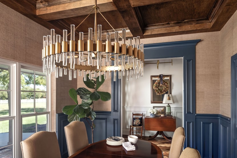 Dining room with grass cloth wallpaper and blue paneling, decorative chandelier