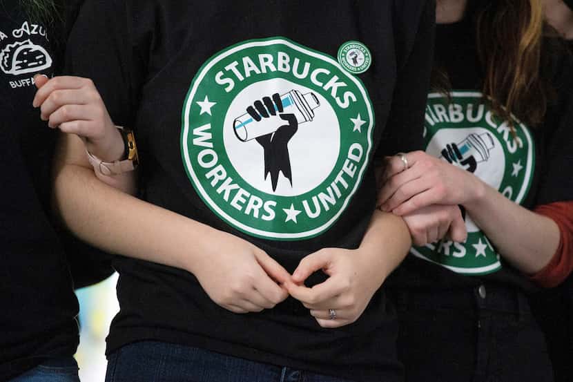 Starbucks employees and supporters link arms during a union election watch party a couple...