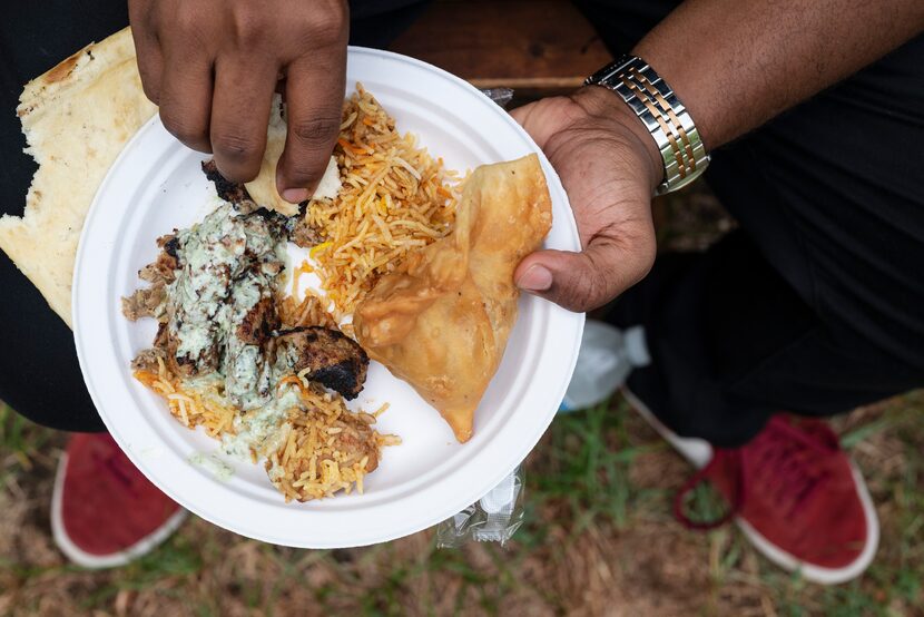 Abdelhalim Awadalla, 28, eats from a plate of Chicken Biryani, Samosa, and Seekh Kebab,...