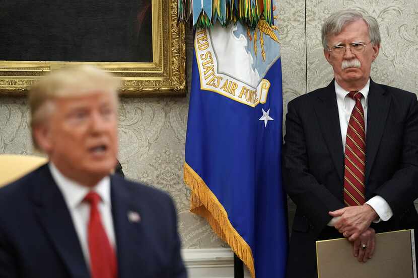 Former national security adviser John Bolton (right) listens as President Donald Trump...