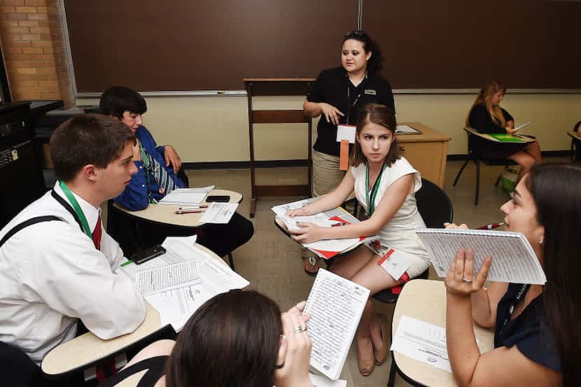 Baylor admission counselor Gina Romero (standing) helps a team of students as they practice...