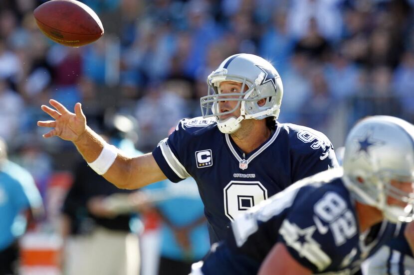 Dallas Cowboys quarterback Tony Romo (9) reaches for an errant snap during their NFL game...