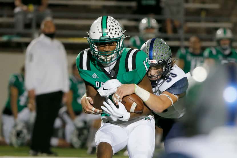 Southlake Carroll's R.J. Maryland (left) makes a reception as he is hit by Northwest Eaton's...
