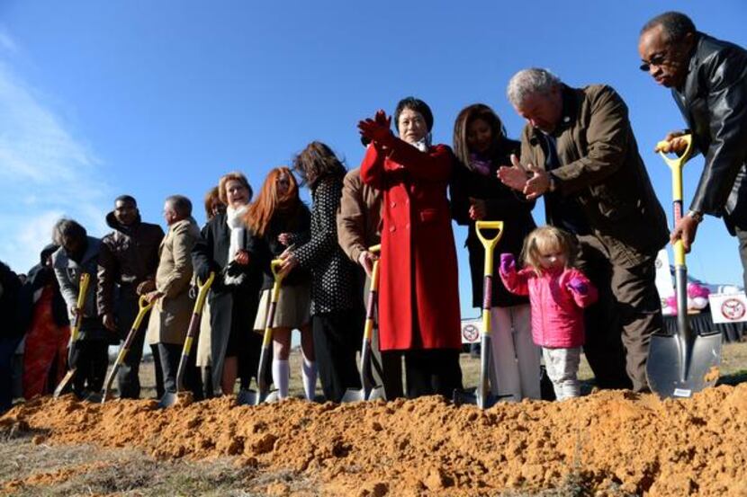 
School officials and family members participate in a ceremonial groundbreaking for...