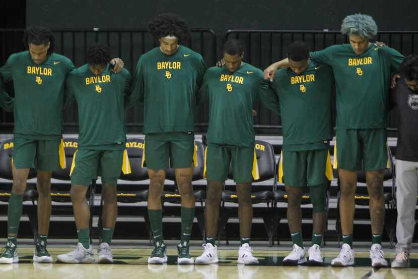 Baylor Bears players pause for a prayer at courtside before the opening tip of their game...
