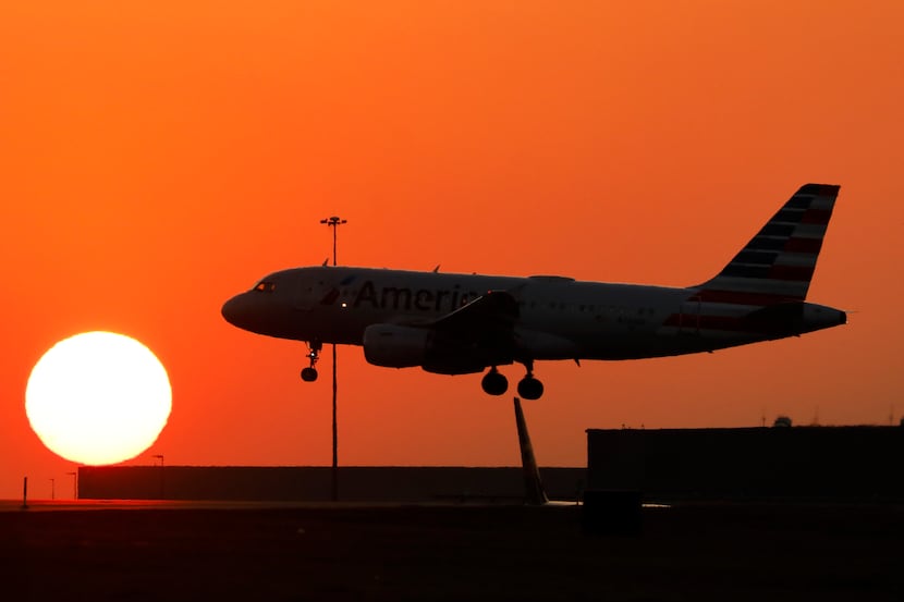 An American Airlines jet lands before the setting sun at DFW Airport, February 15, 2023.